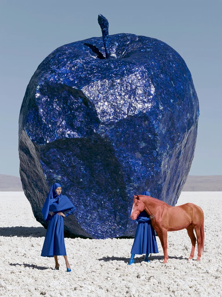 A giant cobalt mineral apple on white salt with a woman in a blue dress and a reddish horse