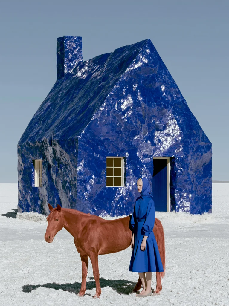 A cottage of glossy cobalt mineral on a salt flat with a woman in blue beside a reddish horse