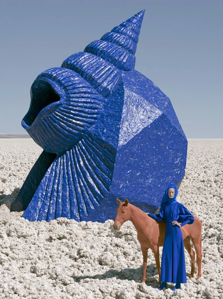 A colossal cobalt mineral seashell in a white salt desert with a woman in blue and a red horse