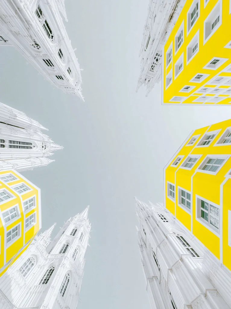 White gothic cathedrals with lemon yellow walls seen from below around an open pale sky