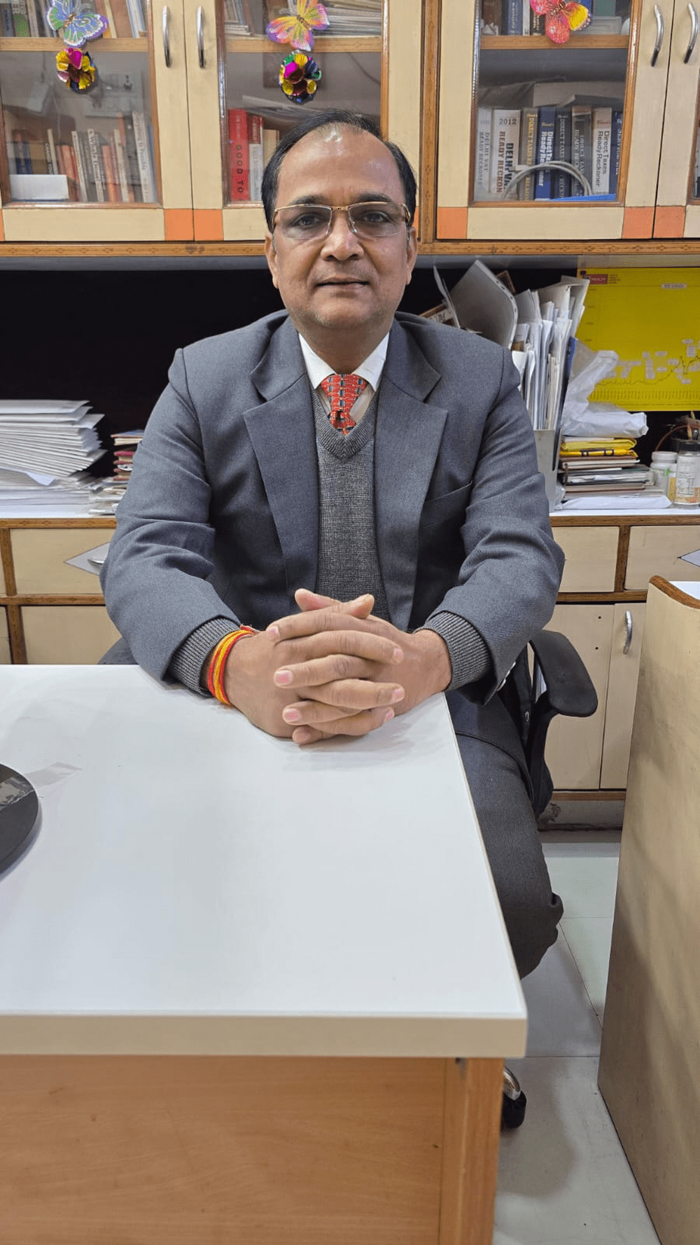 A man in a suit sitting at a desk with grey background table increase from right side