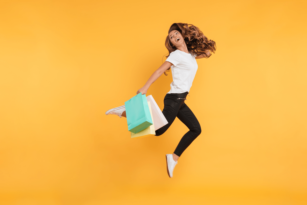 Joyful Young Woman Jumping with Shopping Bags