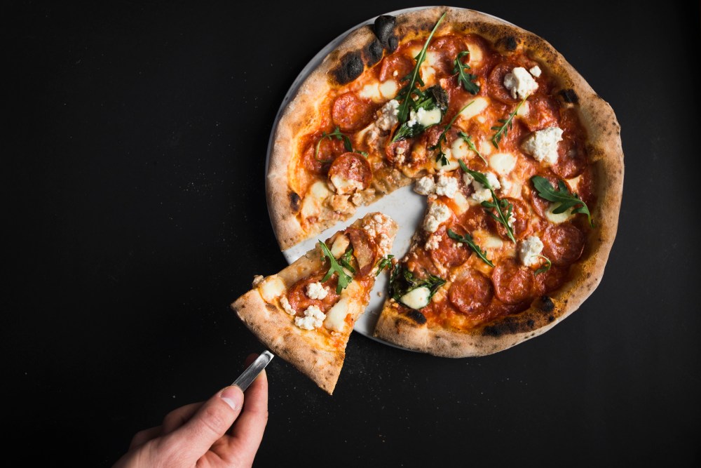 Crop hand taking piece of pizza