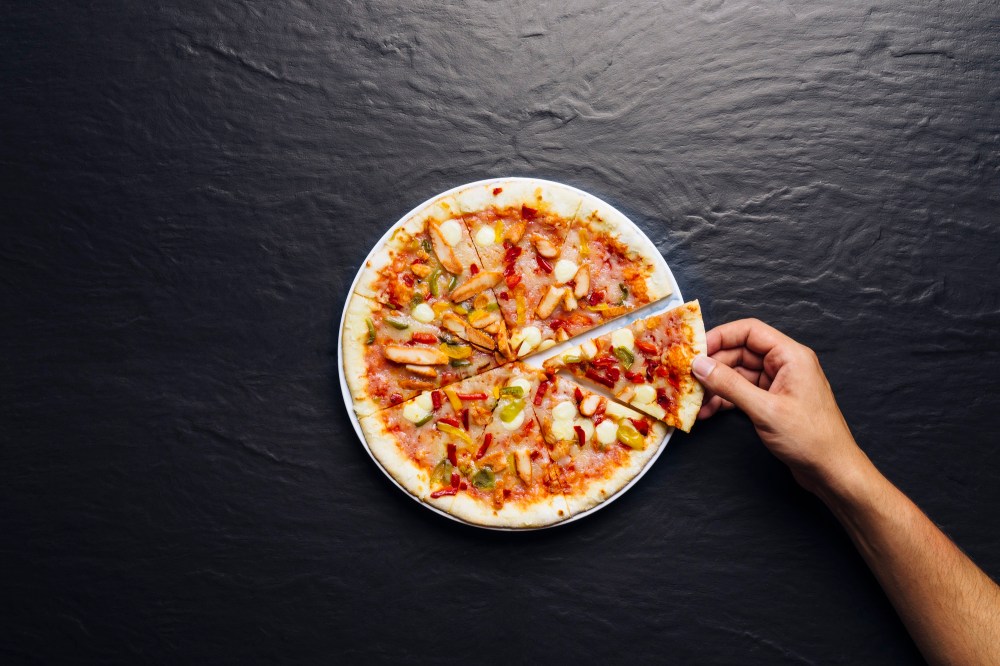 Hand taking slice of pizza