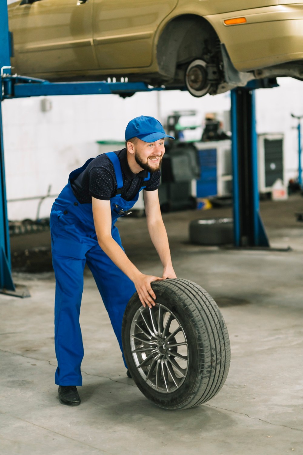 Mechanic rolling wheel to car elevator