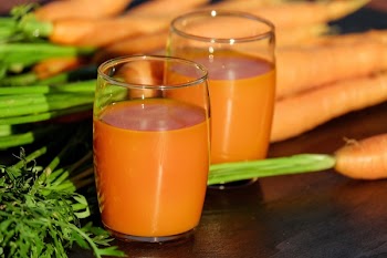 2 Clear Drinking Glass Container with Carrot Juice on Brown Wooden Tabletop in Tilt Shift Lens Photography