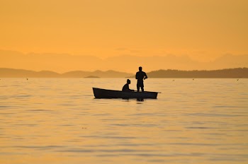 2 People Standing Sitting in a Boat on Body of Water