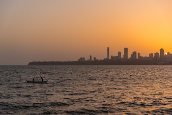 2 Person on the Boat on the Ocean in Front Urban City during Golden Hour
