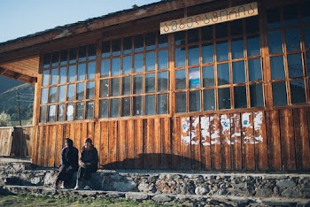 2 Person Sitting by Cabin
