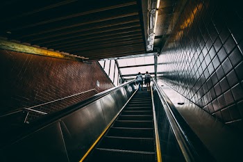 2 Person Standing on Black Escalator during Daytime