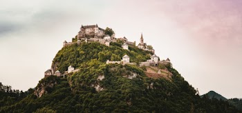 A Beautiful Castle Built On Top Of A  Mountain Surrounded By Trees