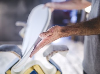 A blurry shot of a man's hands holding a handmade part of a surfboard