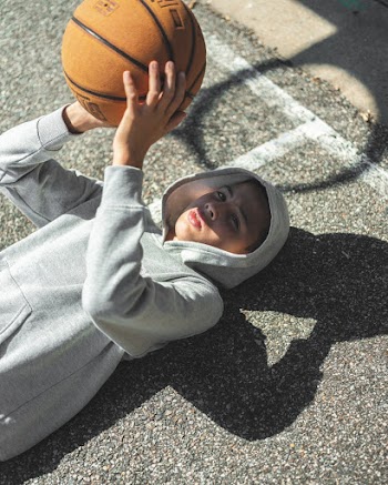 A Boy In A Hoodie Lying On The Floor With A Basketball In Hand
