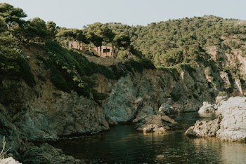 A Building Close To A Cliff Of A Mountain With Lush Vegetaion