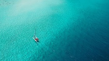 A catamaran sails across a shallow reef in the Maldives