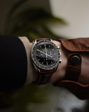 A close up of a Omega Speedmaster "Sapphire Sandwich" Moonwatch on a Hirsch padded leather strap.
