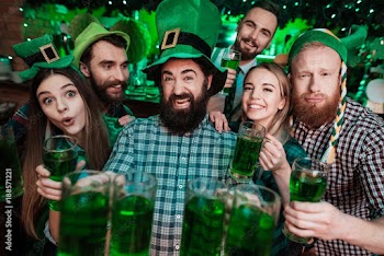 A company of young people posing on the camera with glasses of beer in their hands.