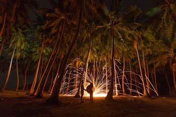 A couple holds hands in front of sparks in a tropical forest in the Maldives