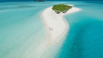 A couple walks hand-in-hand on a beautiful deserted beach in the Maldives