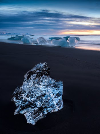 A crystal clear iceberg washed up on the black volcanic sands of the beach at Jökulsárlón, Iceland (Glacier Lagoon). This image was shot at sunrise.