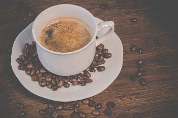 A Cup of Coffee on Brown Wooden Table With Coffee Seeds