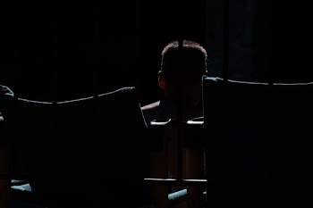 A dim shot of a silhouette of a man behind bars