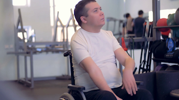 A disabled man is stretching his arms and shoulders while sitting ...