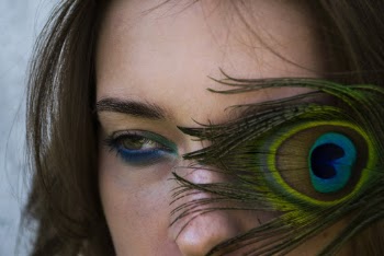 A Feather Covering An Eye Of A Woman's Face