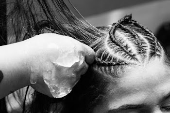 A gray scale photo of a woman's hair being plaited