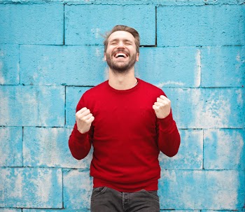  A happy young caucasian man in red sweater standing against a br 