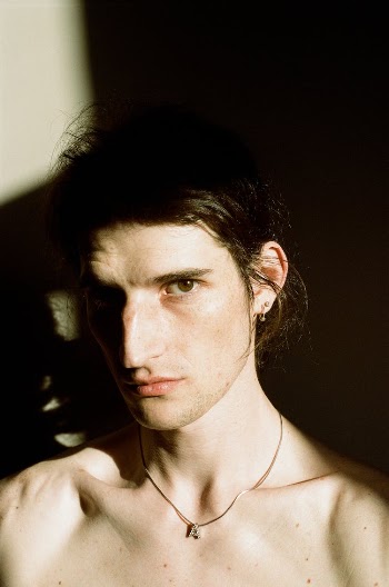 A Headshot of a Male Looking at Camera and Half of His Face Covered in Shadow 