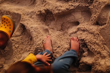 A Kid Sitting on Brown Sand