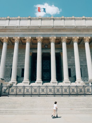 A kid skating in front of the justice court in Lyon, France. I love the way the coud is right where it needs to be in order to see the flag.