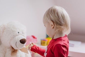 A little girl feeding her teddy