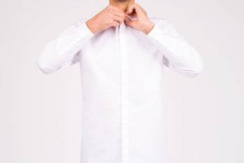 A man buttoning up a white shirt