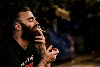 A Man Holding Smoking a cigarette and Holding a Lighter