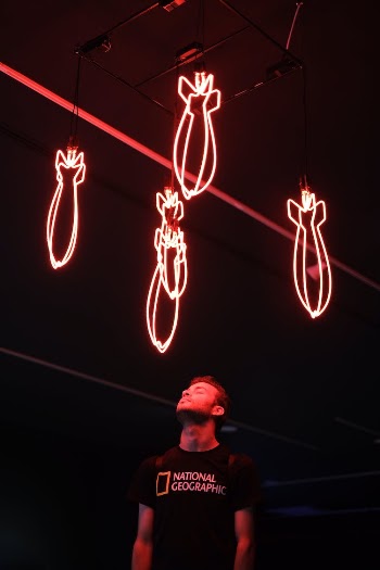 A Man in Black Shirt Standing Under the Neon Lights