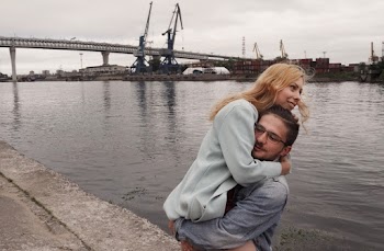A Man Standing Near Body of Water lifting a woman