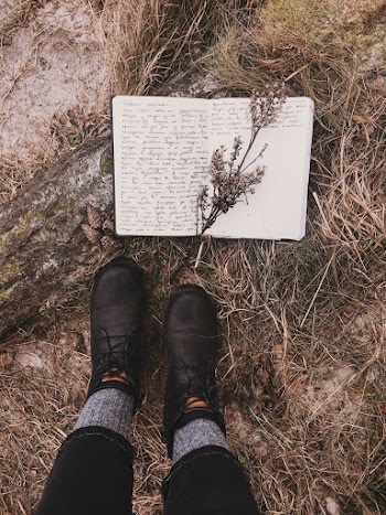 A man wearing a Pair of Black Leather Boots standing near a book