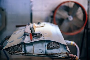 A metal junk part with tools on it in a garage with a fan