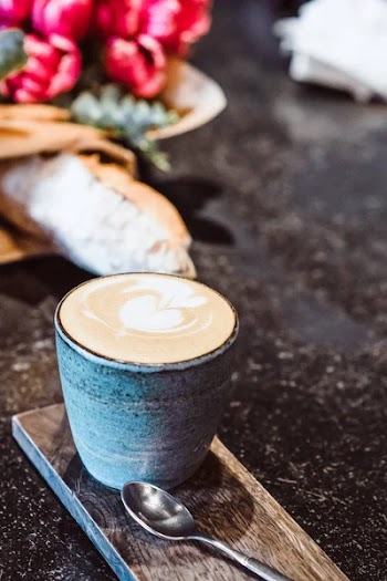 A mug with coffee cappuccino on the table in a cafe. Smartphone, bouquet of flowers and cappuccino. Organization of space on the table