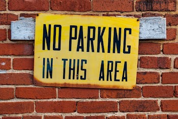 A no parking sign on a brick wall   