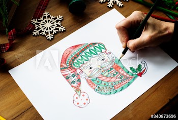 A person drawing a colorful Santa Claus' face