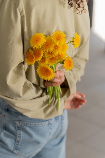 A Person Holding Yellow Flowers at Her Back