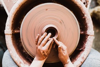 A person's hands crafting pottery on a spinning wheel