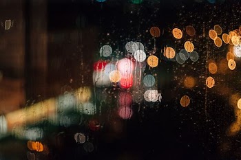 A rain-streaked window with a bokeh effect