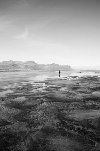 A Silhouette of a Person Standing on Beach Shore in Grayscale Photography · Free Stock Photo