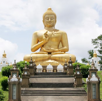A sitting Buddha statue against a blue sky.