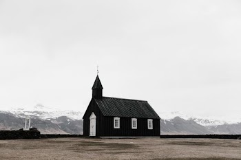 A small chapel in a plain with snowy mountains on the horizon