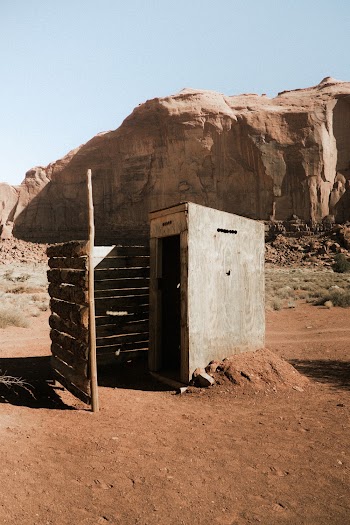 A Small Concrete Structure With A Wooden Fence Built Close To A Rock Mountain In The Desert